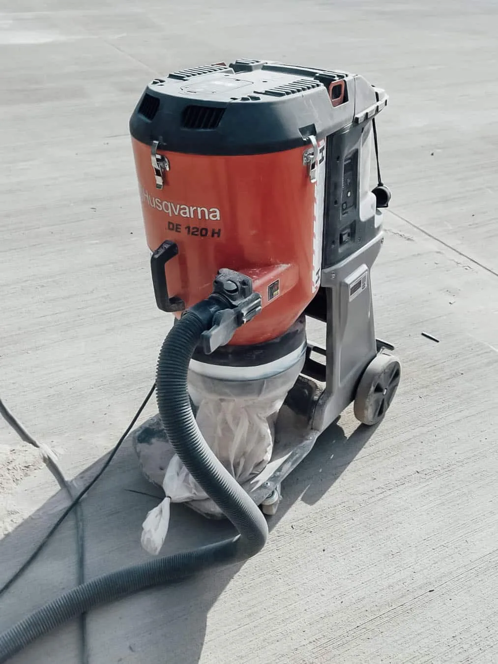 Industriesauger mit Schlauch auf einem geschliffenen Hallenboden