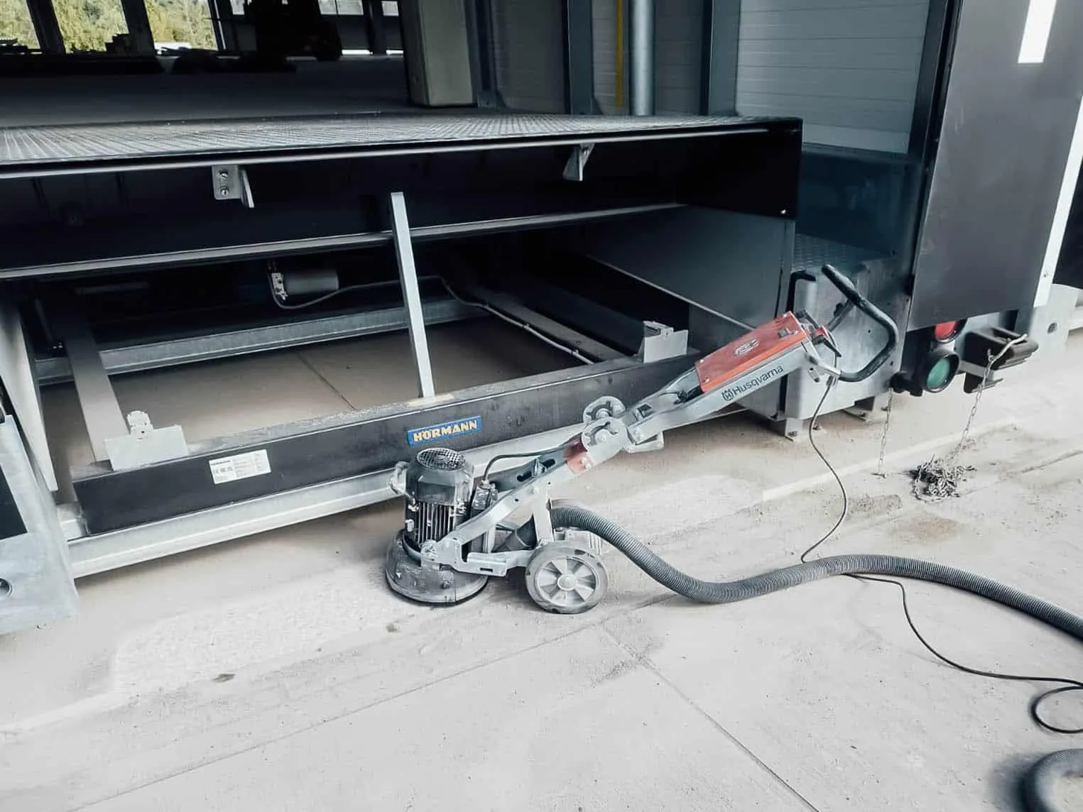 Schleifmaschine neben einer Stahlkonstruktion auf dem Hallenboden