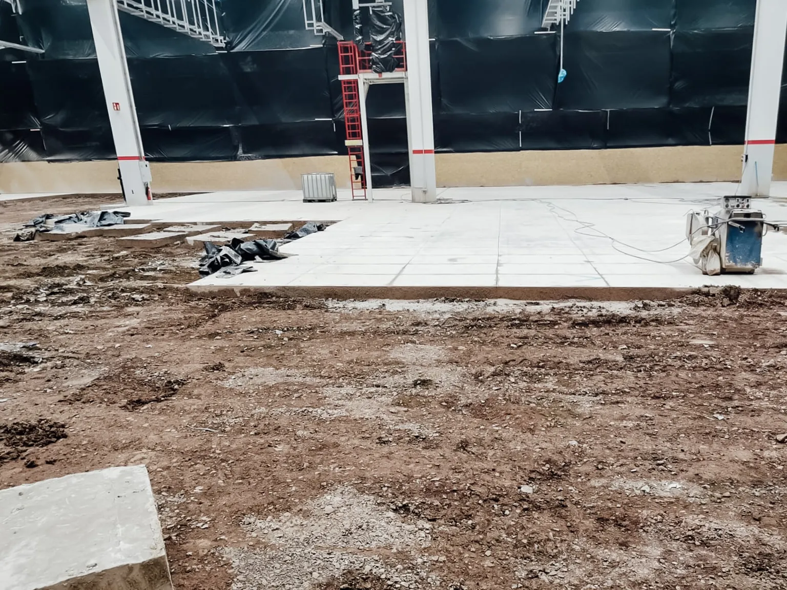 Halle mit geöffnetem Boden: herausgenommener Betonabschnitt und freigelegtes Erdreich