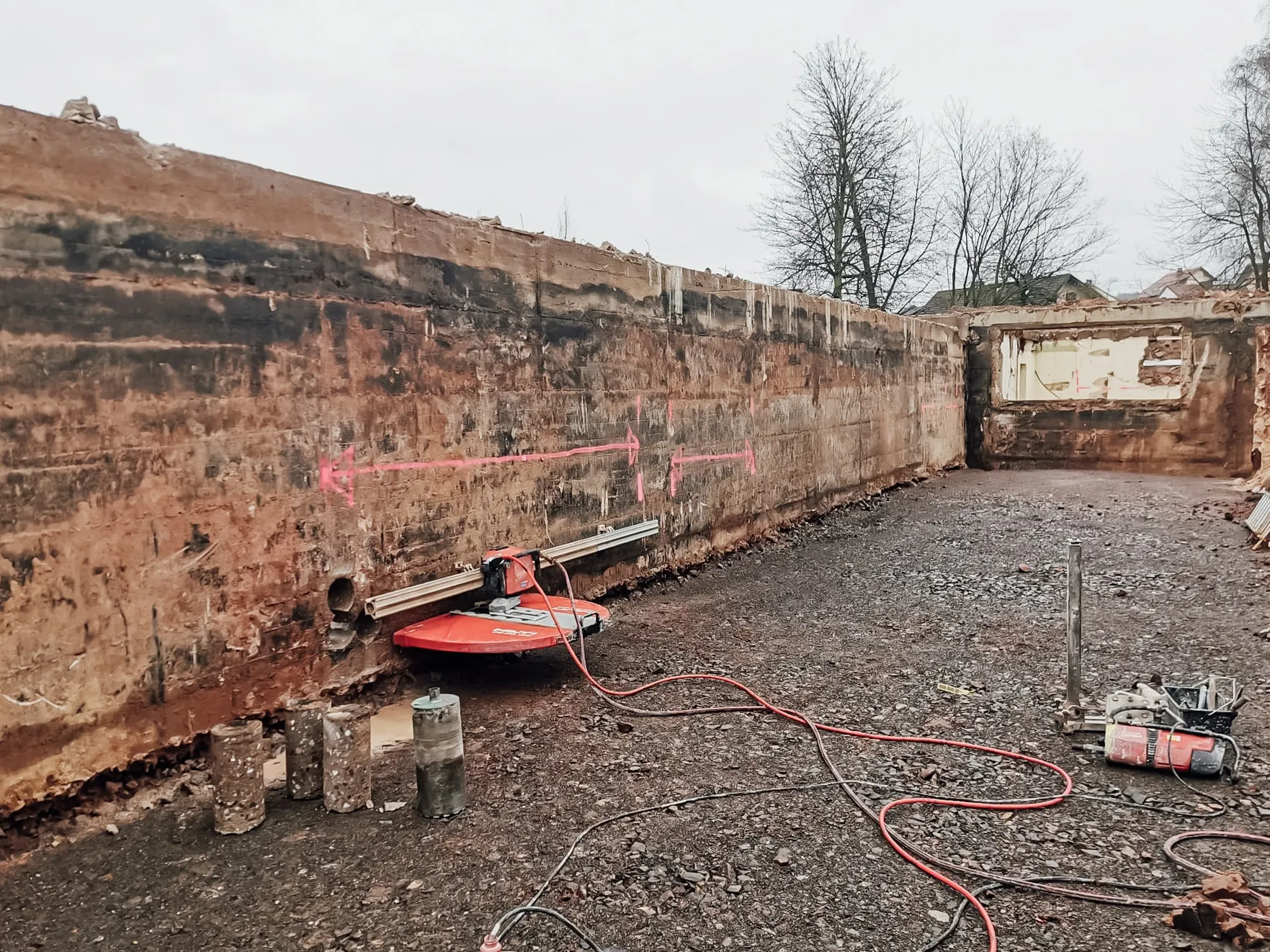Lange Baugrube mit gesägter Betonwand und roter Wandsäge auf der Führungsschiene