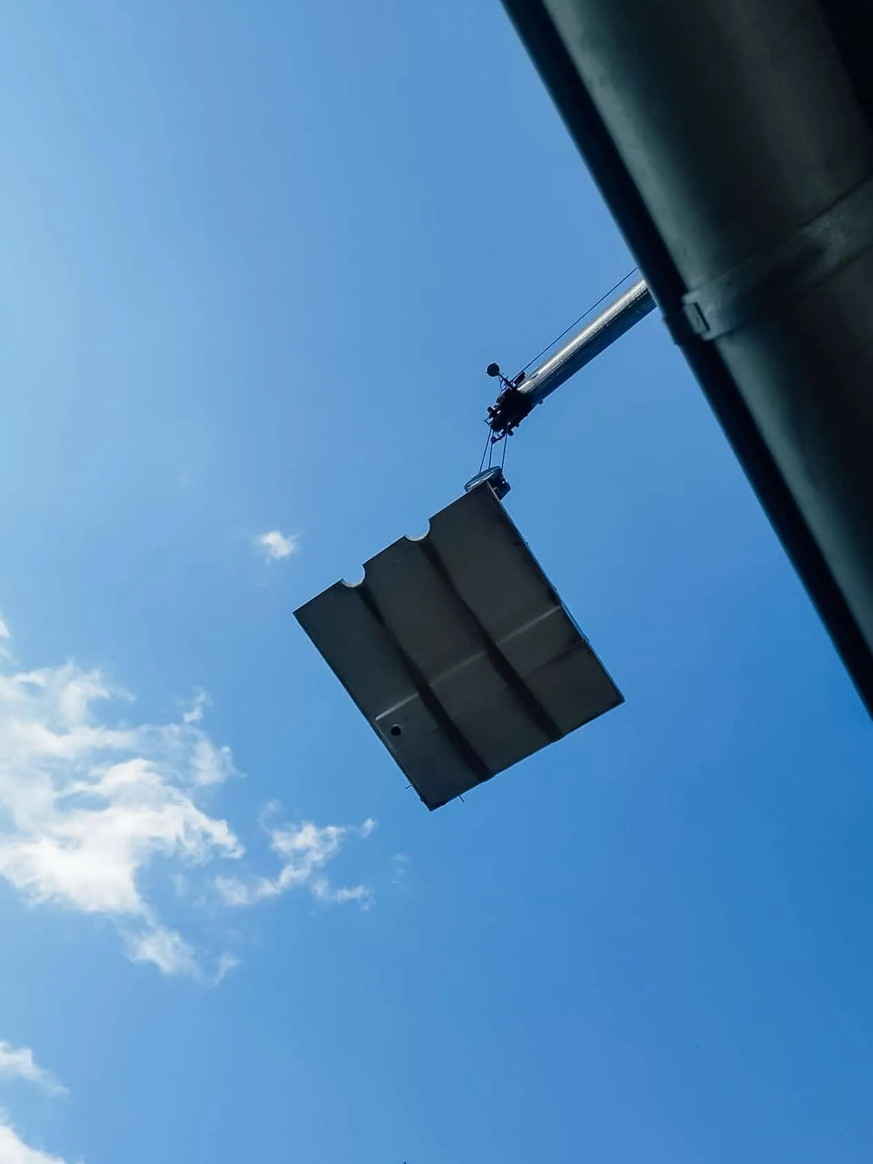 Herausgesägtes Betonteil hängt an einem Kran vor blauem Himmel